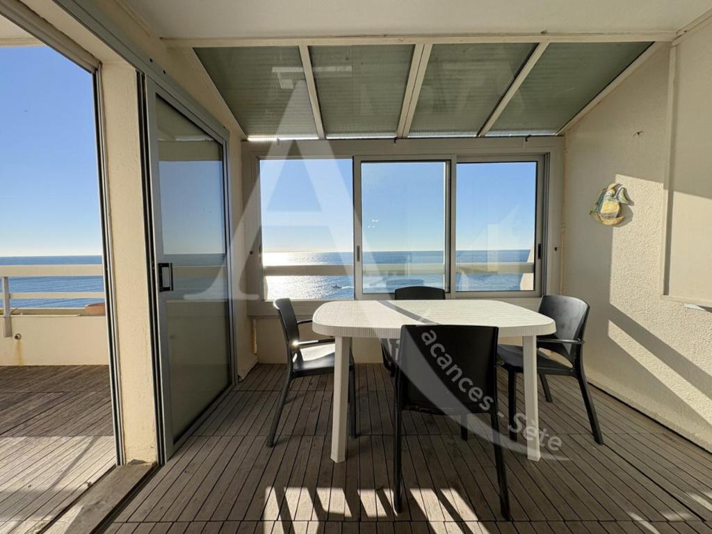une salle à manger avec une table et des chaises sur un balcon dans l'établissement T2 vue mer avec parking et wifi, à Sète