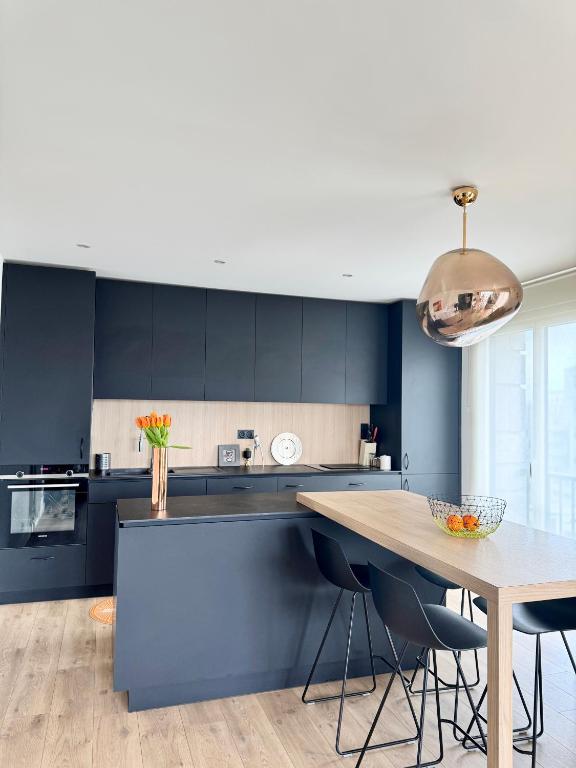 une cuisine avec des placards bleus et une table en bois dans l'établissement L'Aristide, Centre de Rennes avec vue Vilaine, à Rennes