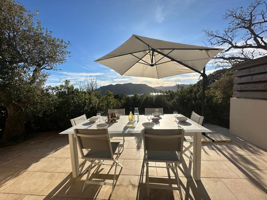 une table blanche avec des chaises et un parasol dans l'établissement Villa familiale située à 10 minutes à pieds de la plage de Santa Giulia, à Porto-Vecchio