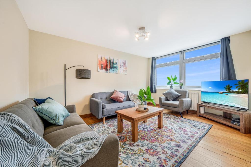 a living room with a couch and a tv at Premier Suites Shepherds Bush Westfields Penthouse Apartment in London
