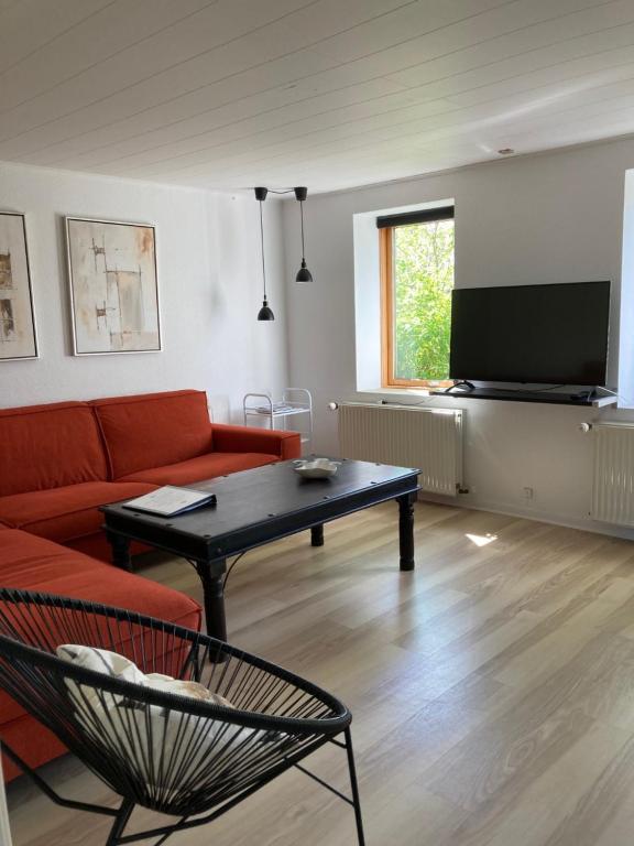 a living room with a couch and a table and a tv at Nymindegab Ridecenter Ferienwohnung in Nørre Nebel