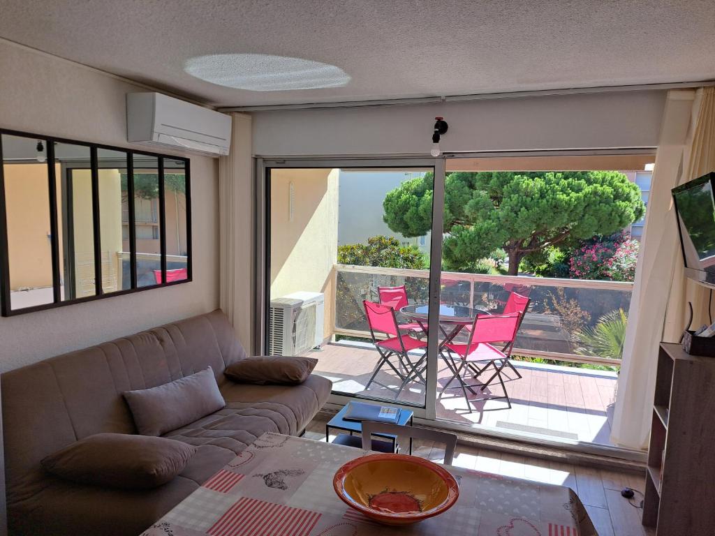 un salon avec un canapé, une table et des chaises dans l'établissement Hélios 32, T2 climatisé, parking, 500m plage, au Cap d'Agde