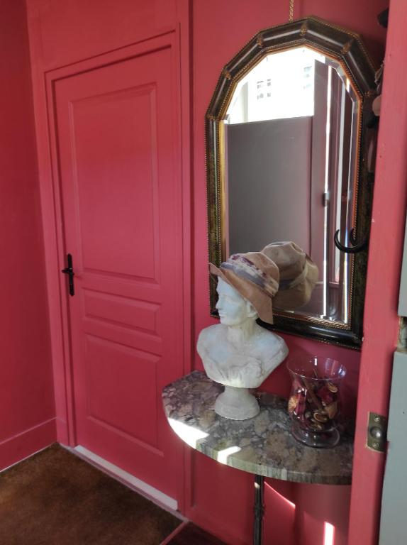 a red room with a mirror and a statue on a table at Studio en ville in Bergerac