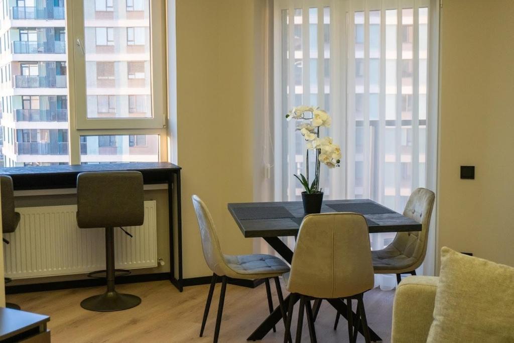 een eettafel met stoelen en een tafel met bloemen erop bij Avenue Boutique Luxury N3 in Chişinău