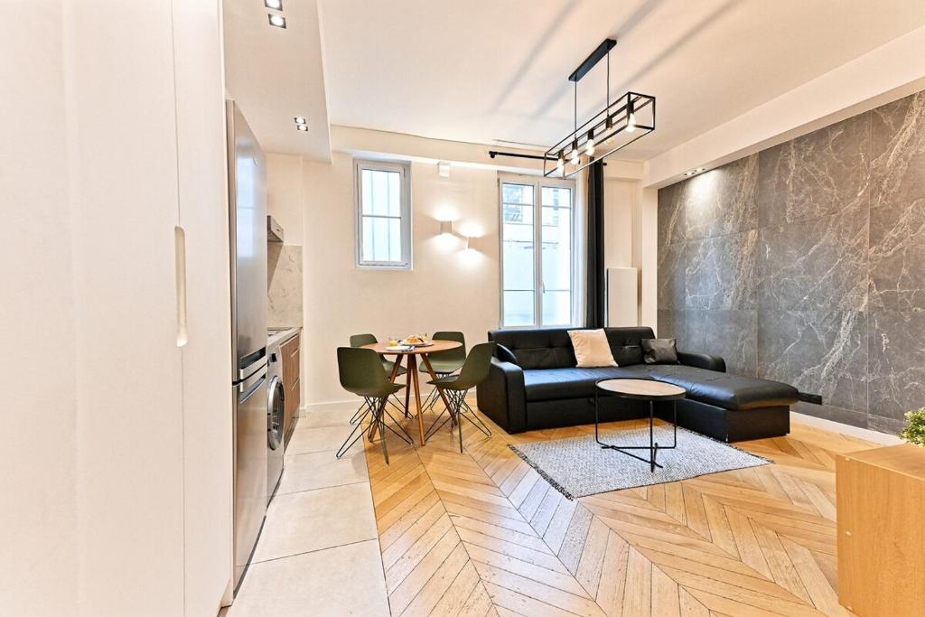 ein Wohnzimmer mit einer schwarzen Couch und einem Tisch in der Unterkunft Studio Raffiné près de la Seine Paris 16ème in Paris