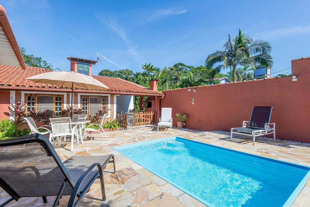 una casa con piscina con sedie e ombrellone di Casa com piscina a 100 m de Camburizinho a Camburi