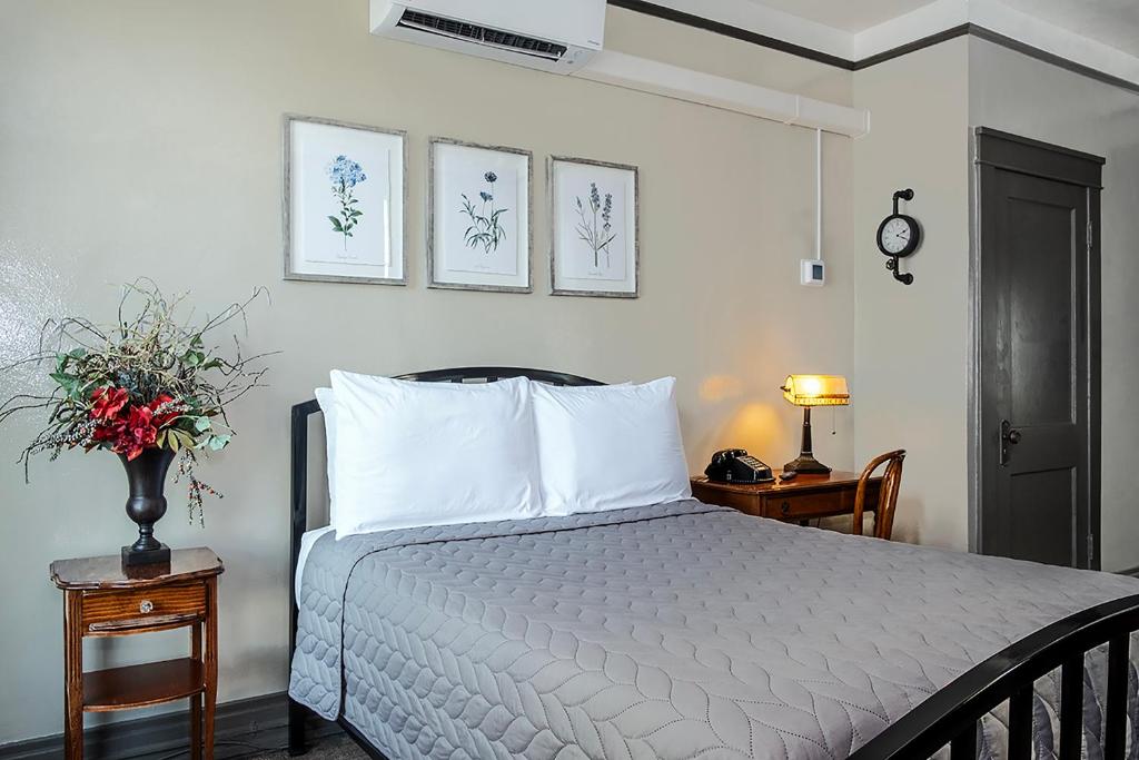 a bedroom with a bed with white sheets and a table at Gardner Hotel & Hostel in El Paso
