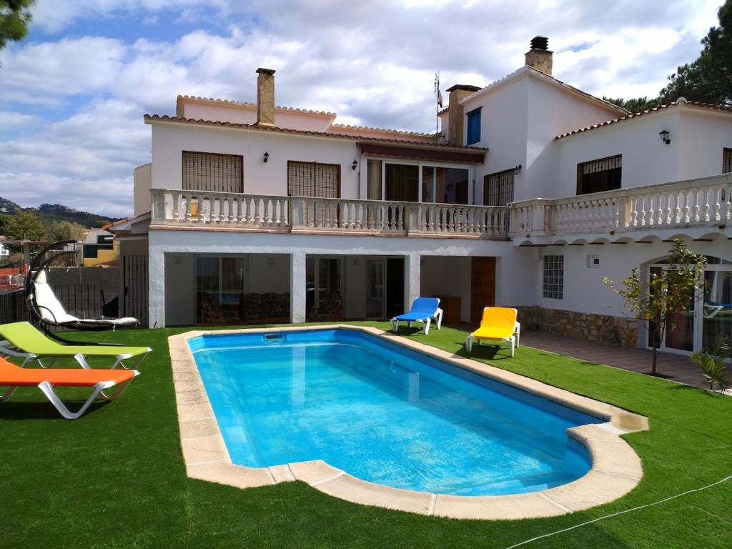 a villa with a swimming pool in front of a house at Allotjament Bogues in Lloret de Mar