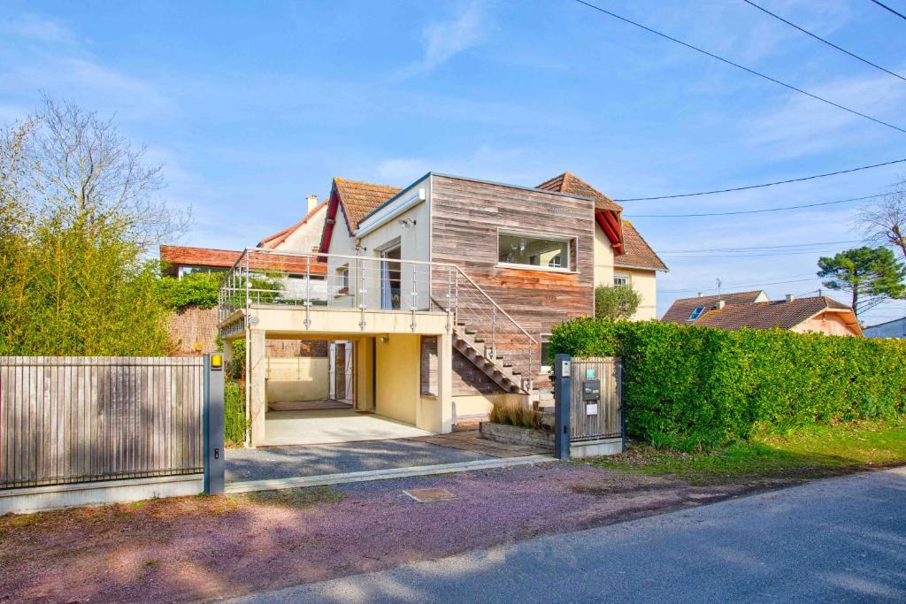une maison avec une façade en bois et une clôture dans l'établissement Villa Garcane à 200 m de la mer - Cabourg, à Varaville