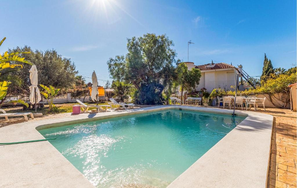 a swimming pool in a yard with chairs and a house at Stunning Home In El Campello in El Campello