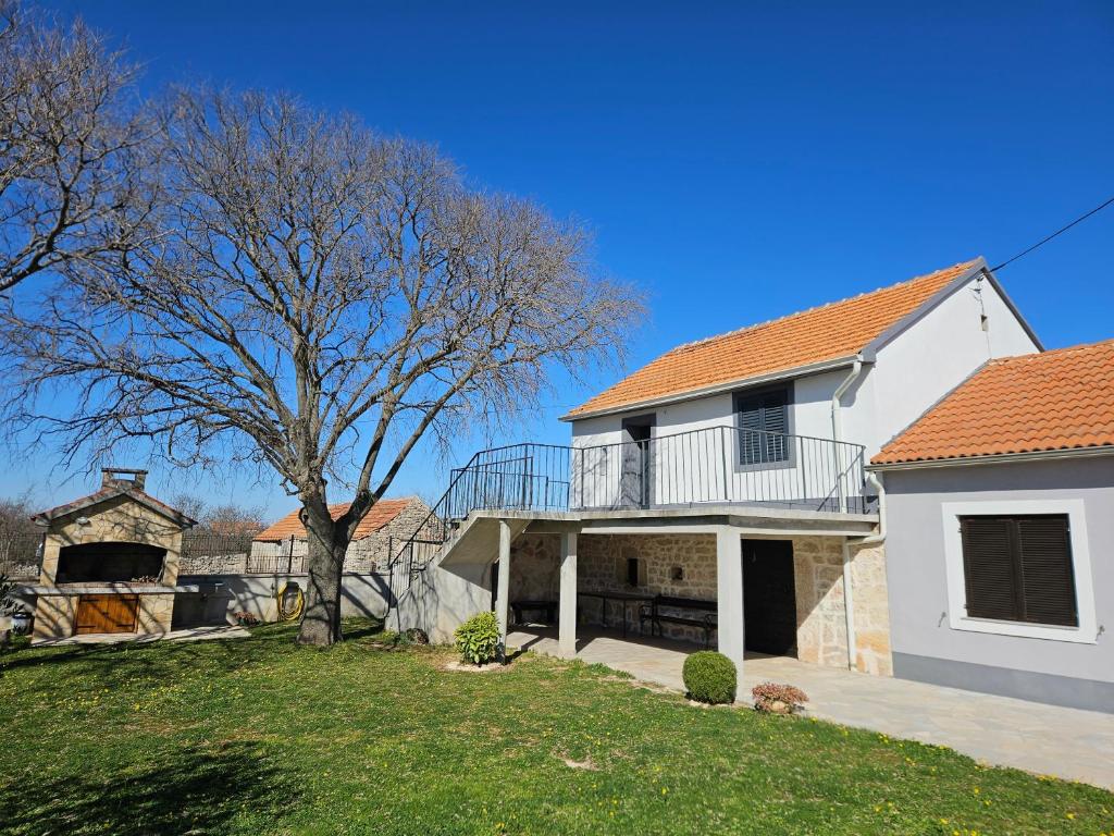 a white house with a balcony and a tree at Holiday Home Nena in Drniš