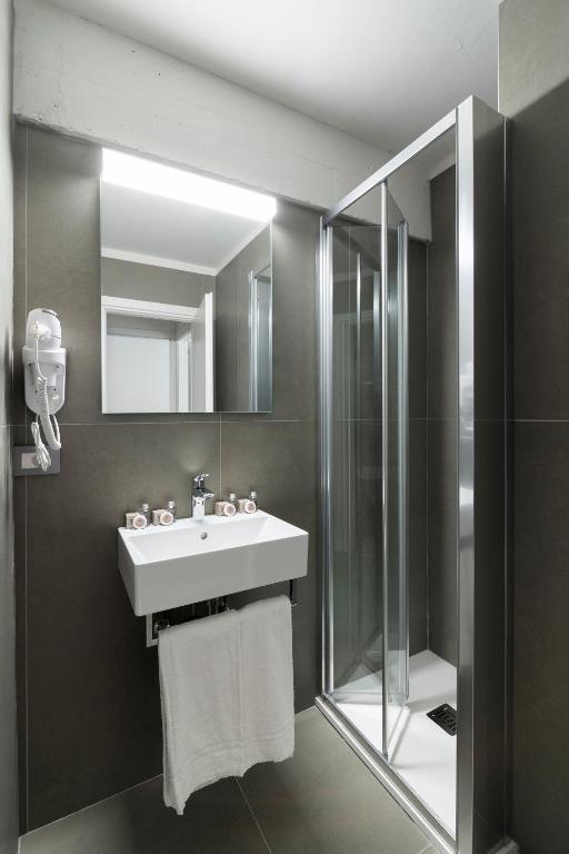 un bagno con lavandino e doccia di Appartamenti Corte Residence a Borca di Cadore