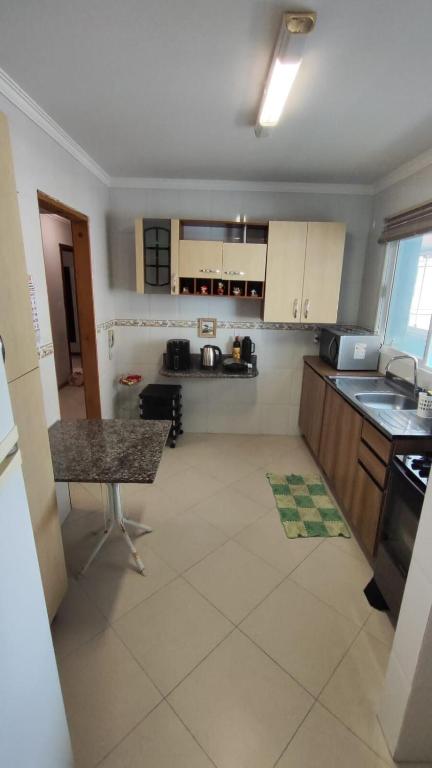 a kitchen with white cabinets and a counter top at Half Beach Apartment - Itapema in Itapema
