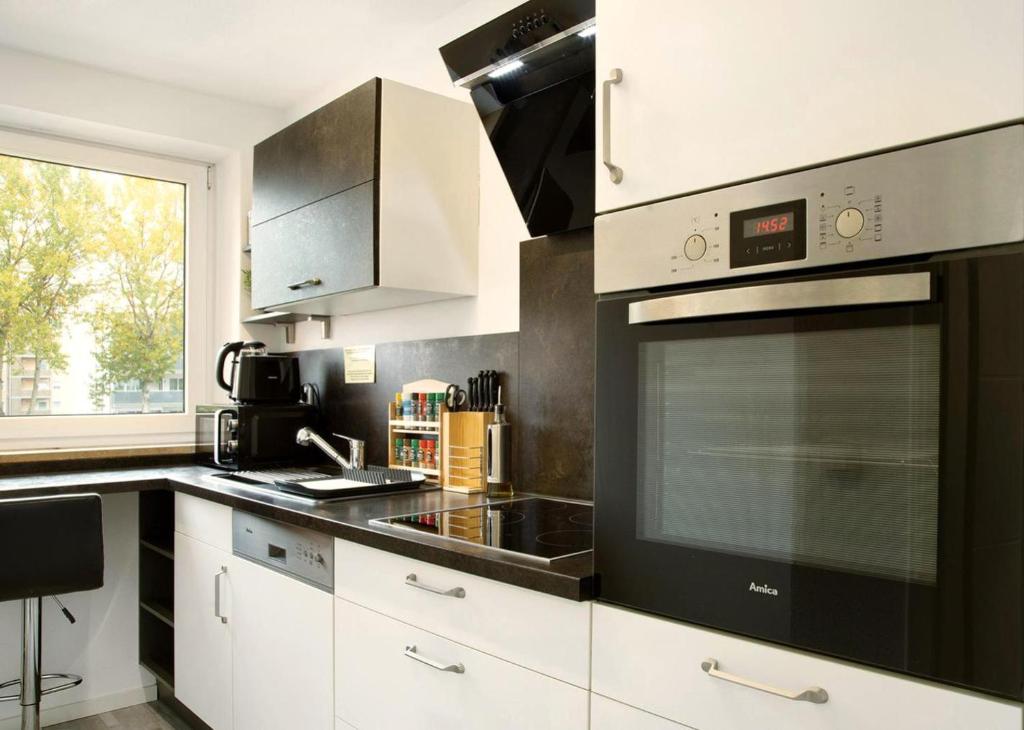 a kitchen with white cabinets and a black stove top oven at Modern Apartments Neuburg S - NEU - 2 Zimmer, Parkplatz, Wi-Fi, TV, Küche in Neuburg an der Donau