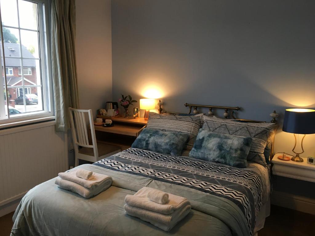 a bedroom with a large bed with towels on it at Leafy Suburban Bed and Breakfast in Northwood