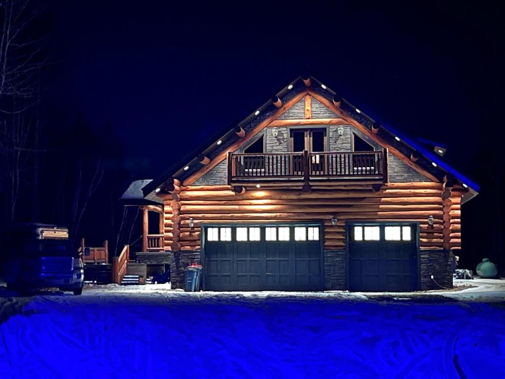 a log cabin with a balcony and a garage at night at Southview Lodge in Valemount