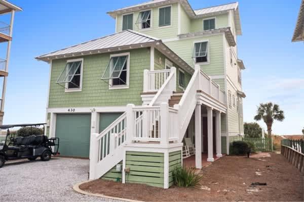 a green house with a white porch and a driveway at NEW- Gulf Front home 4 bed 4 bath in Indian Pass