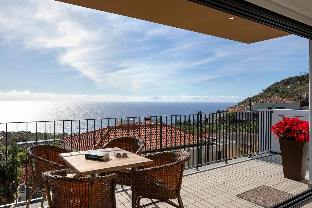 a balcony with a table and chairs and the ocean at Marco 4 Seasons- Summer in Arco da Calheta