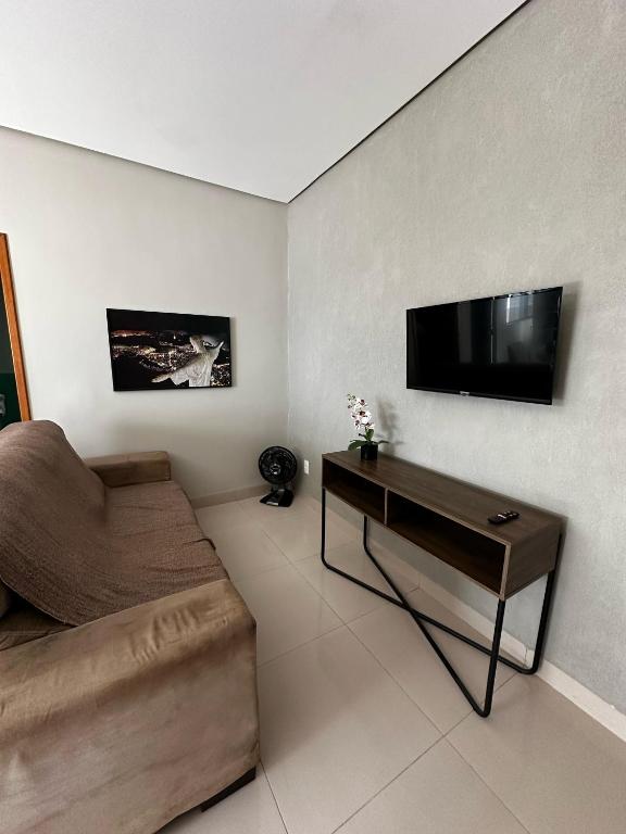 ein Wohnzimmer mit einer Couch und einem Fernseher an der Wand in der Unterkunft CASA 04 próximo ao Centro in Palmas