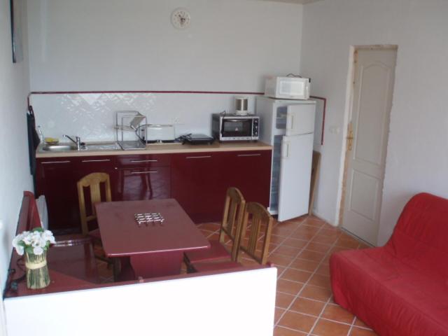 une petite cuisine avec une table et un canapé rouge dans l'établissement location Champagné, à Champagné