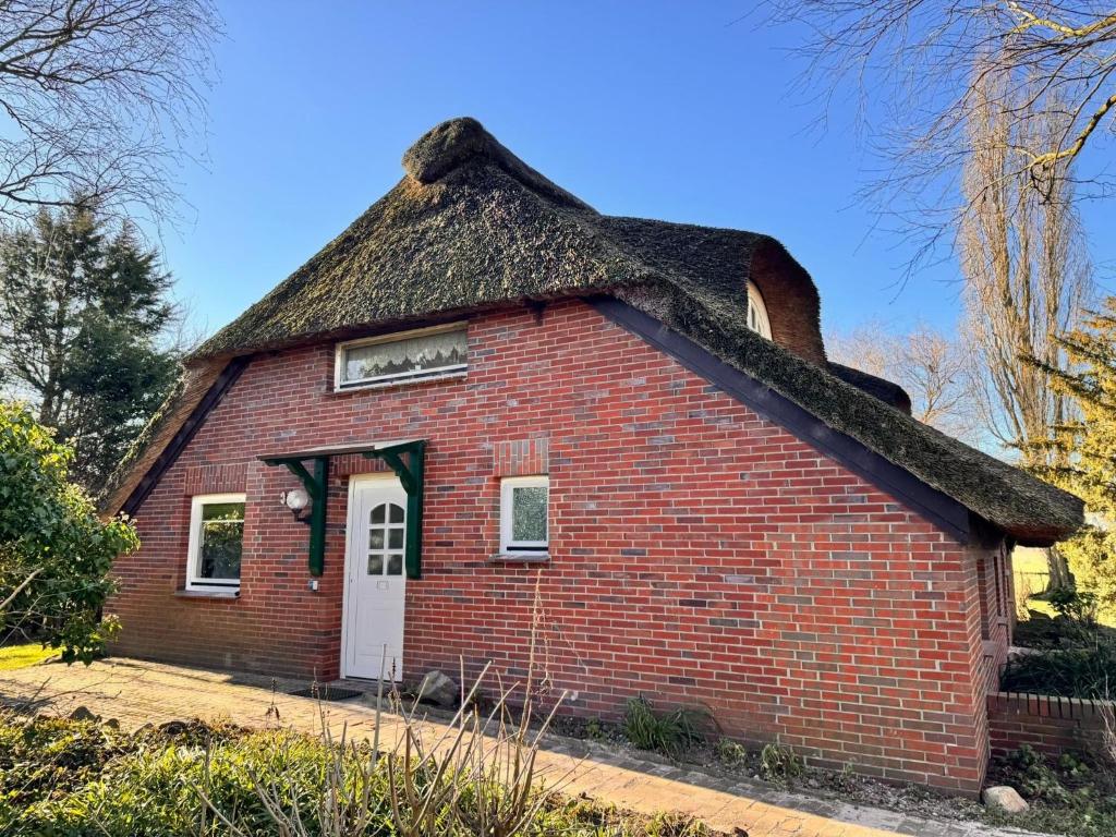 a small brick house with a thatched roof at Ferienwohnung im Reetdachhaus, Burhave in Burhave