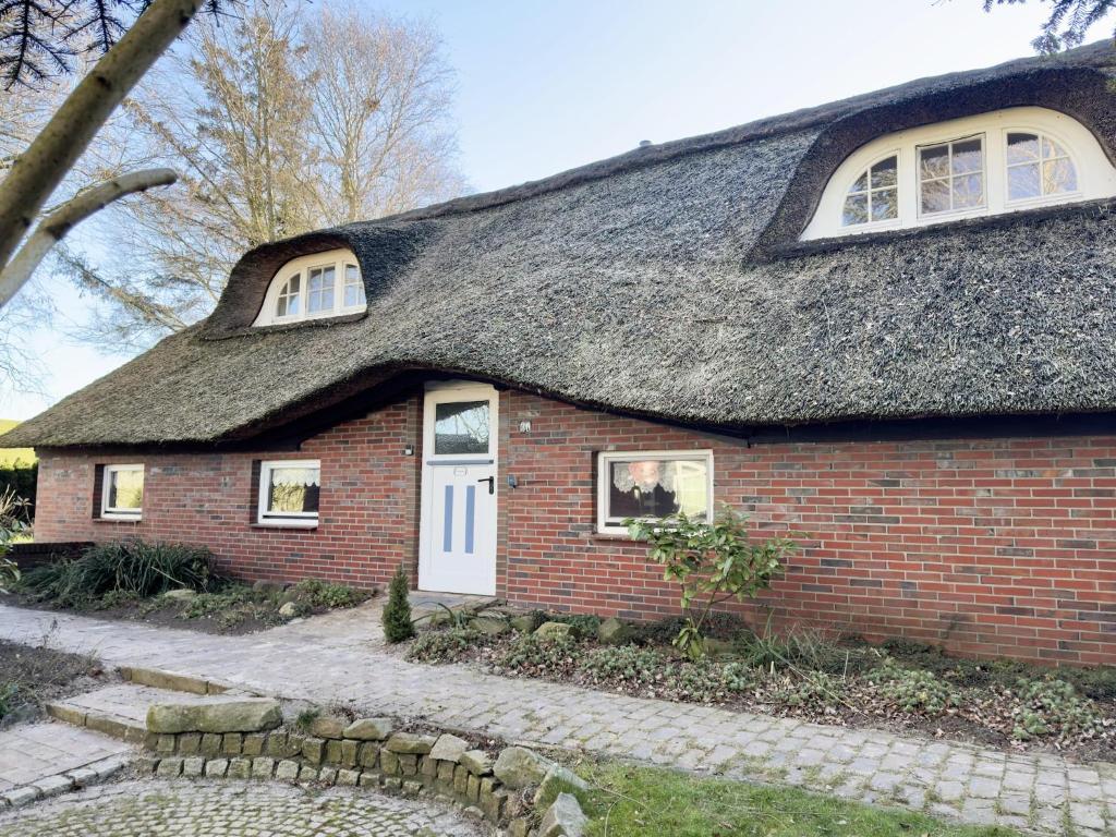 a red brick house with a thatched roof at Ferienwohnung im Reetdachhaus, Burhave in Burhave
