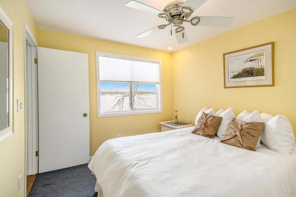 a bedroom with a white bed with a ceiling fan at Pure Michigan At Pine Lake - Swim, Boat, Fun! in Plainwell