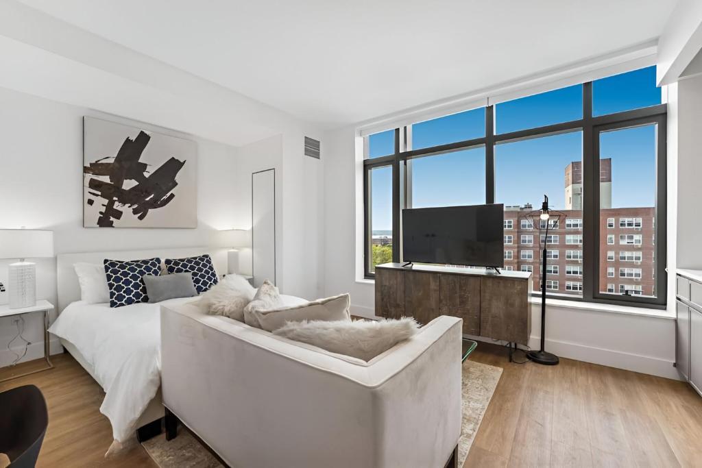 a white living room with a couch and a tv at Elite Brooklyn Living with Premiere Amenities in Brooklyn