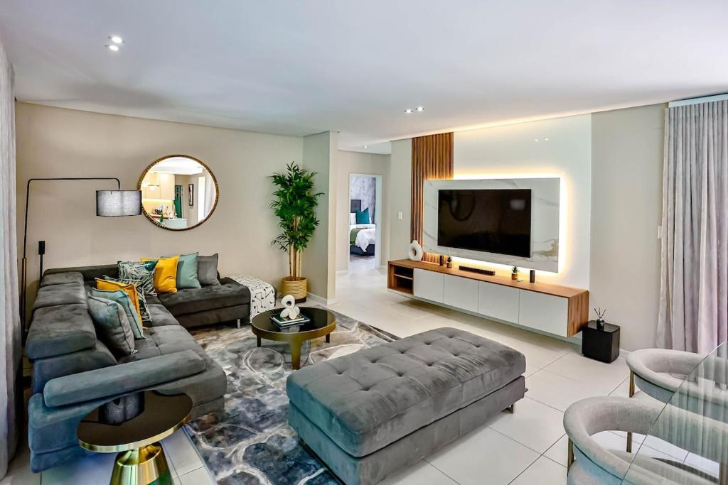 a living room with a couch and a flat screen tv at CasaDulce Zimbali- Exquisite 4 bedroom home with expansive yard and pool in Ballito