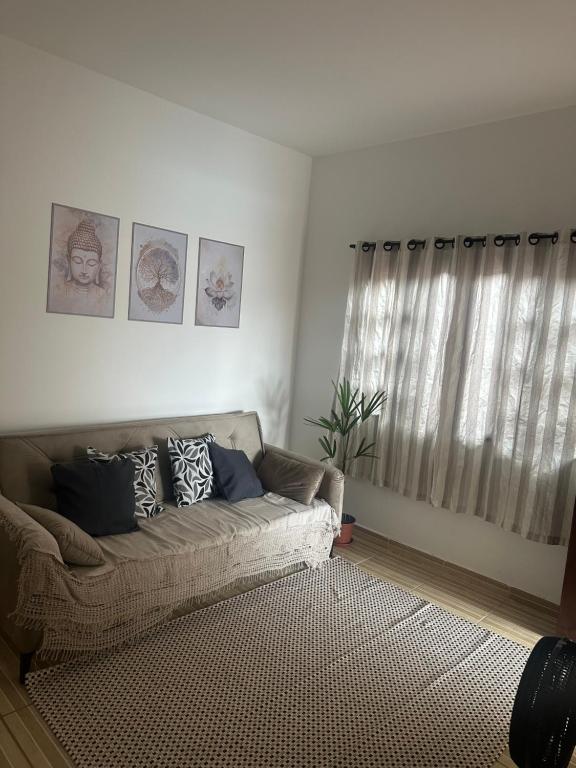 a living room with a couch in front of a window at Casa Itanhaém Multicultural in Itanhaém