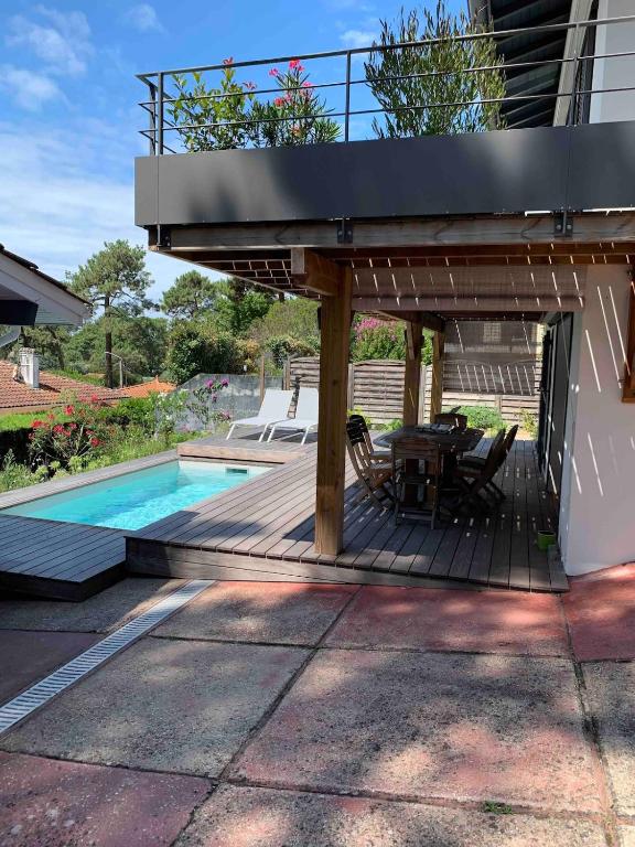 une maison dotée d'une terrasse avec une table et une piscine dans l'établissement Villa avec piscine au Pyla, à La Teste-de-Buch