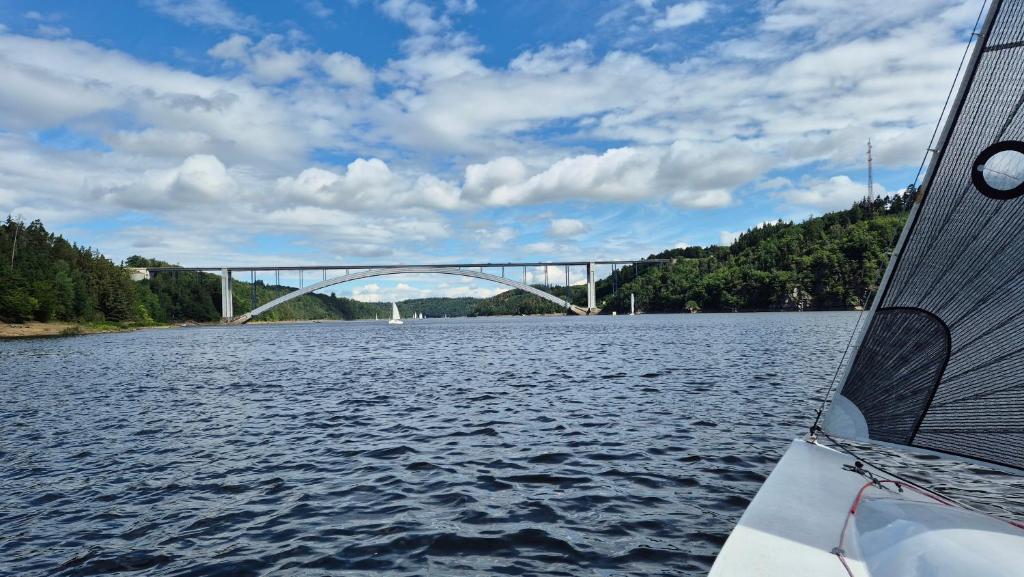 a bridge over a river with a boat in the water at Orlická přehrada Chata Malá in Kožlí u Orlíka
