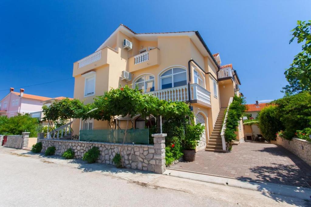 Una gran casa amarilla con plantas delante. en Pension Tina App 1, en Šilo