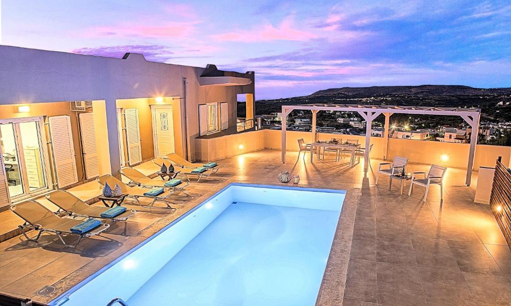 a house with a swimming pool with chairs and a table at Ferienhaus Für 12 Personen In Kournas, Kreta West Kreta in Kournás