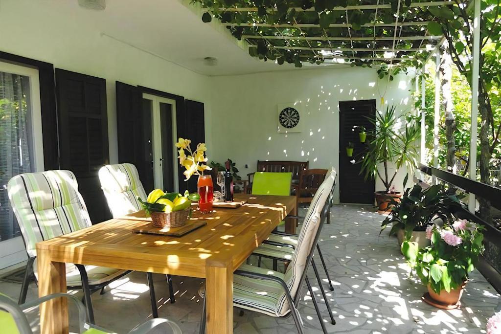 un patio con tavolo e sedie in legno di Ferienhaus Karmen Auf Zwei Ebenen Mit Garten a Orebić (Sabbioncello)