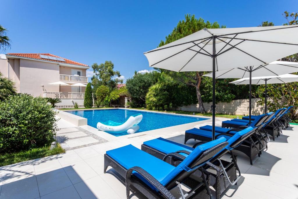 una piscina con sedie a sdraio blu e ombrellone di Geräumige Ferienwohnung Mit Privatem Sonnenbalkon a Splitska