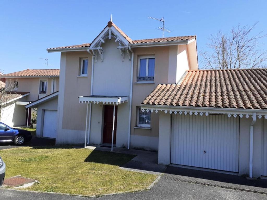 une maison blanche avec deux garages et une voiture dans l'établissement Résidence Closerie De Margot - 019 - Environnement calme pour cette maison pouvant accueillir 4 personnes MAE-4341, à Soulac-sur-Mer