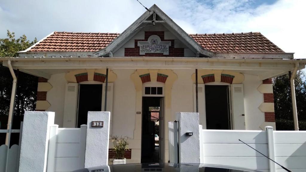 une maison avec une clôture blanche devant elle dans l'établissement Résidence 086-soulac Sur Mer - 086 - Très belle villa Soulacaise au calme et sans vis à vis MAE-4481, à Soulac-sur-Mer