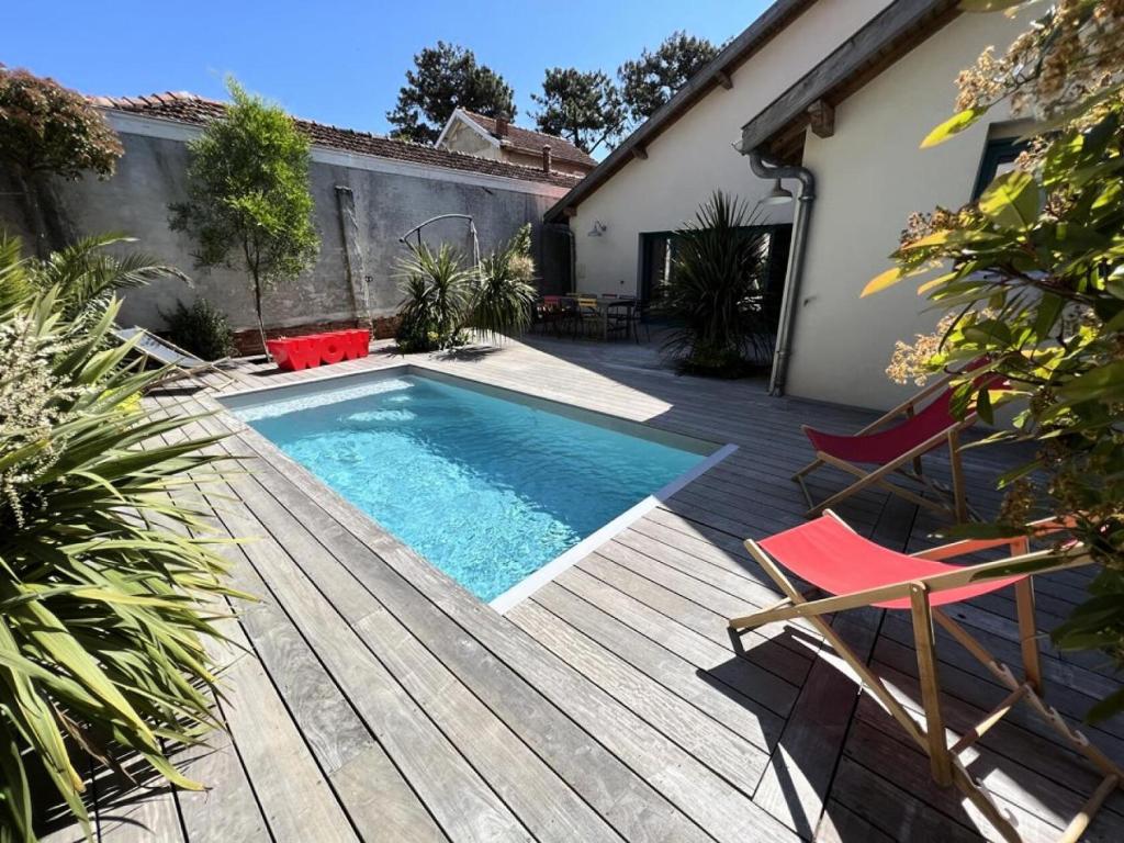 - une piscine sur une terrasse en bois avec 2 chaises dans l'établissement Résidence 023-soulac Sur Mer - 023 - Magnifique villa en duplex avec piscine en plein cœur de la station de Soulac/mer MAE-6041, à Soulac-sur-Mer