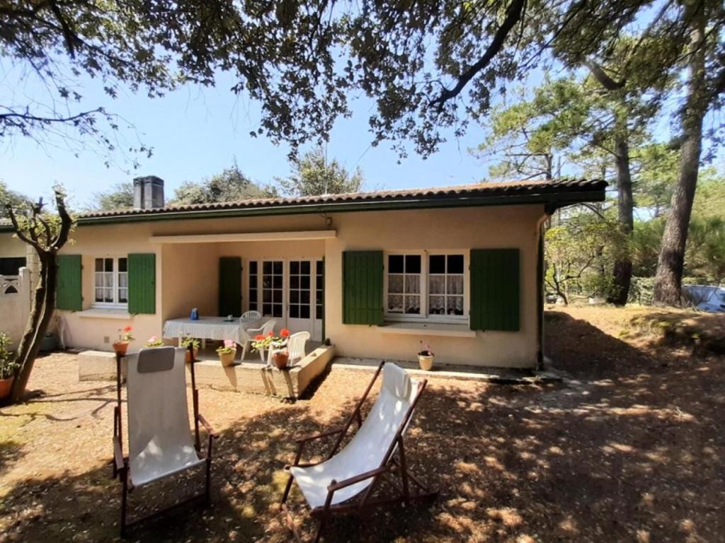 une maison avec deux chaises devant elle dans l'établissement Résidence 062-soulac Sur Mer - 062 - Maison au calme proche des plages et des commerces MAE-6101, à Soulac-sur-Mer