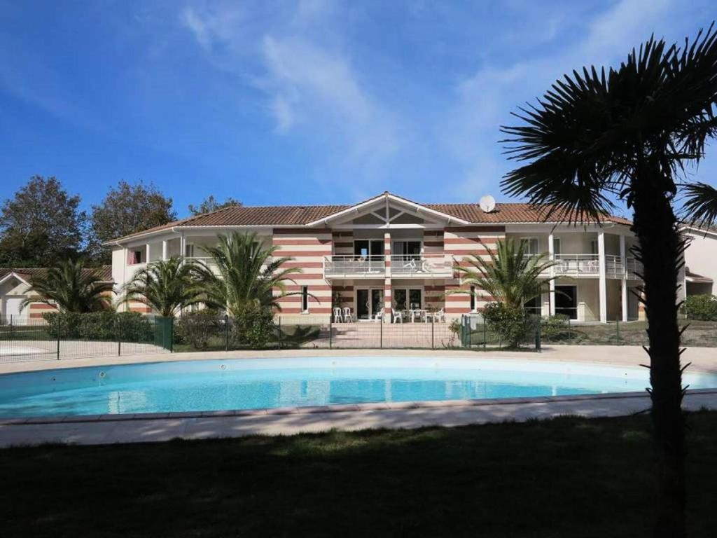 une grande maison avec une piscine devant dans l'établissement Résidence Domaine Des Sables - 037 - Agréable maison mitoyenne dans une résidence de vacances 3 étoiles MAE-3601, à Soulac-sur-Mer