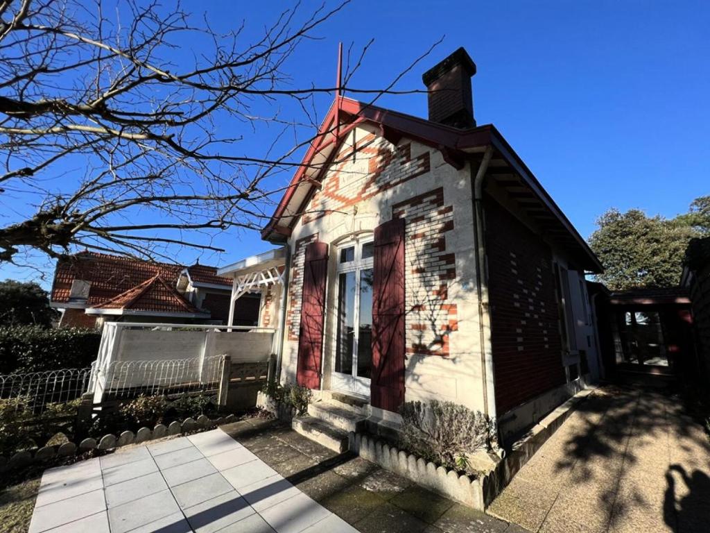une petite maison avec une porte rouge dans une rue dans l'établissement Résidence 056-soulac Sur Mer - 056 - Charmante villa Soulacaise à 2 pas du centre-ville MAE-3631, à Soulac-sur-Mer