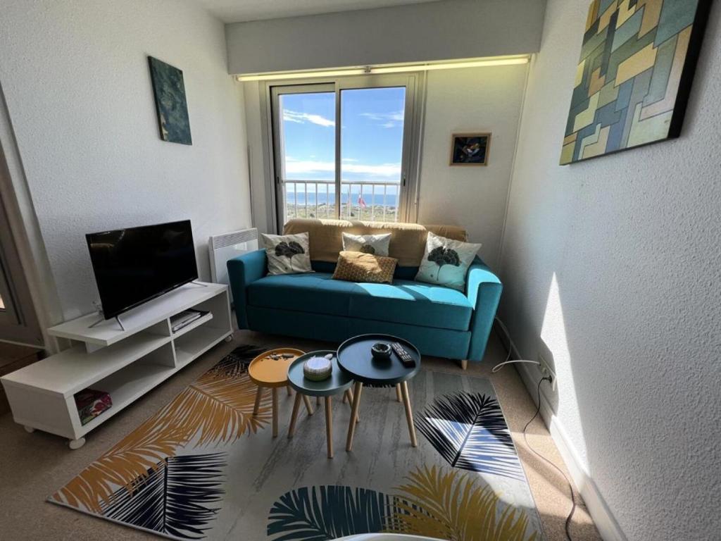 un soggiorno con un divano blu e una televisione di Résidence Marine - 064 - Appartement entièrement rénové et décoré avec goût MAE-6921 a Soulac-sur-Mer