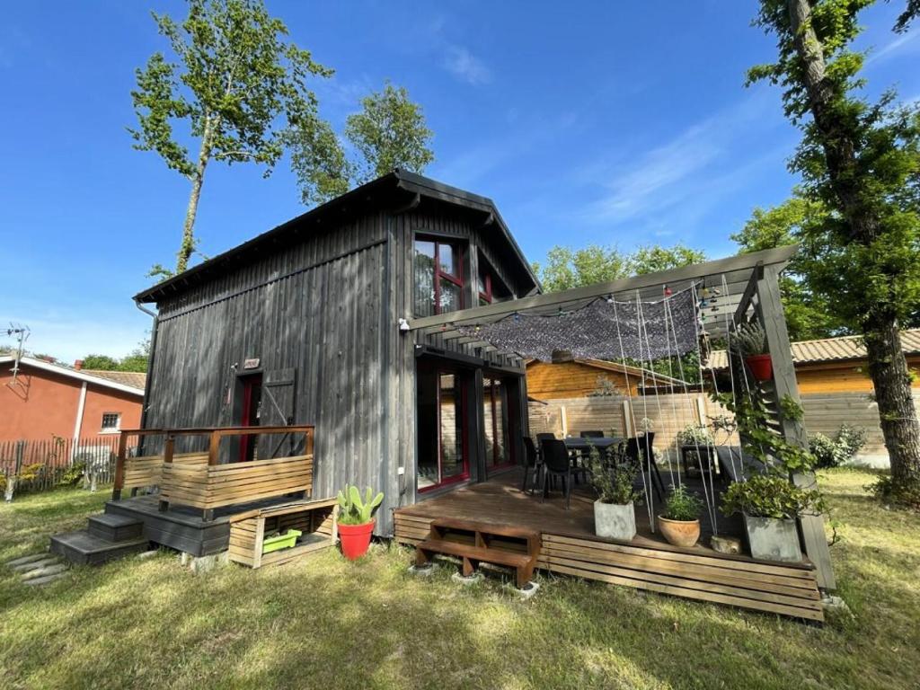 une petite maison noire avec une grande terrasse dans l'établissement Résidence 079-soulac Sur Mer - 079 - Maison en bois décorée avec goût MAE-9691, à Soulac-sur-Mer