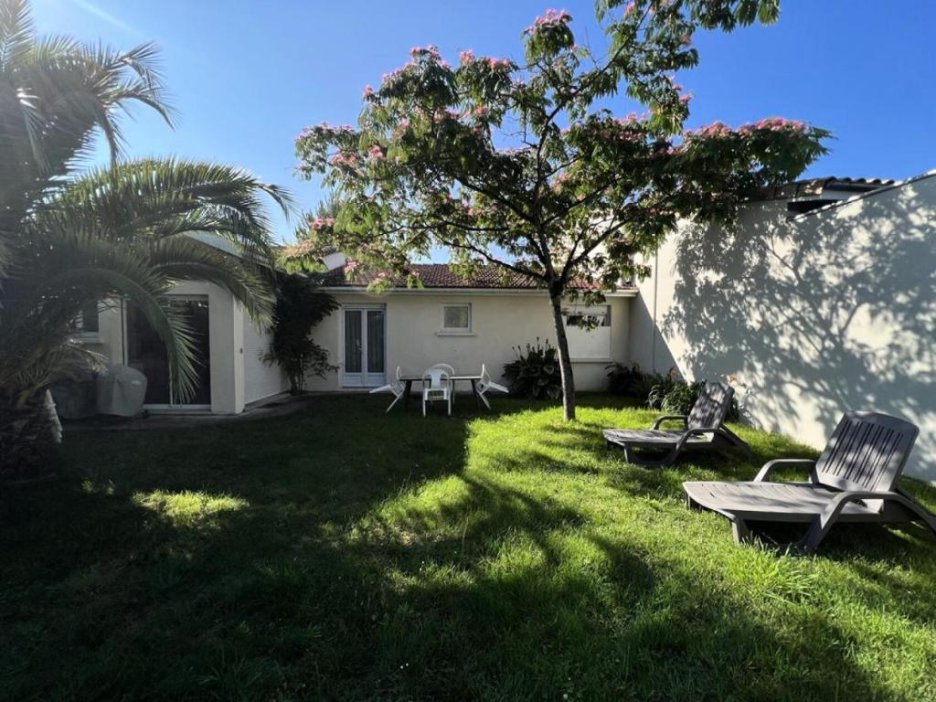 une cour avec deux chaises et un arbre dans l'établissement Résidence 070-soulac Sur Mer - 070 - Maison avec extérieur proche du Centre-Ville MAE-1891, à Soulac-sur-Mer