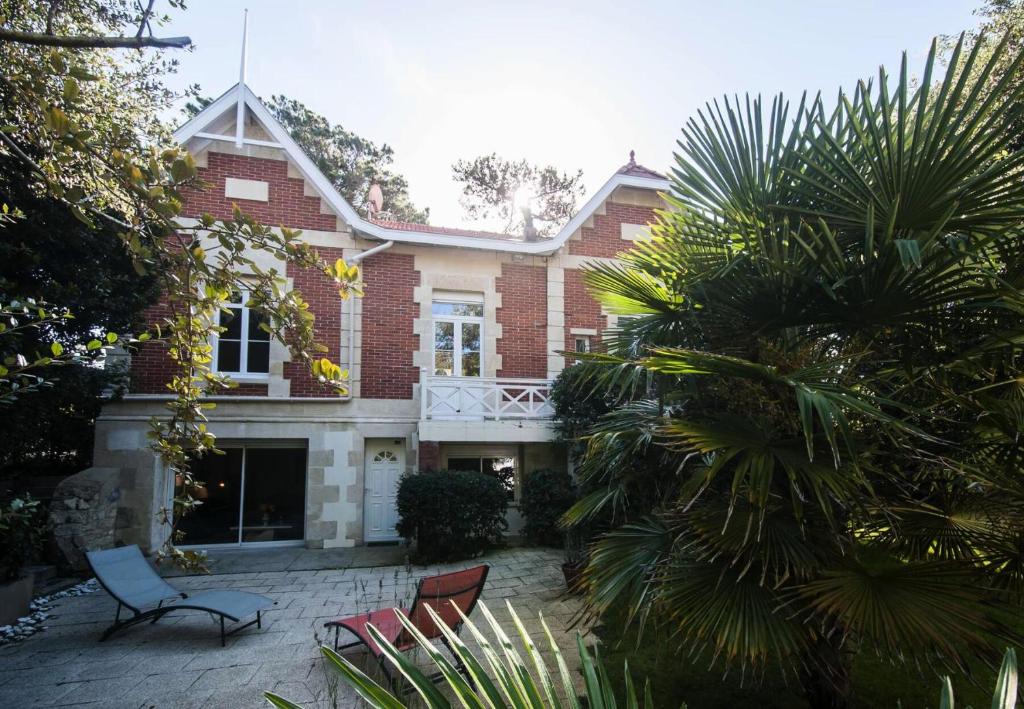 une maison avec des chaises et un palmier en face de celle-ci dans l'établissement Résidence 001-soulac Sur Mer - 001 - Très Belle villa Soulacaise à 5mns du centre MAE-5401, à Soulac-sur-Mer