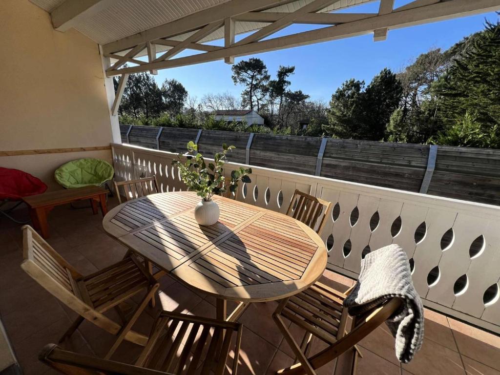 une table et des chaises en bois sur un balcon dans l'établissement Résidence Le Cordouan - 116 - Bel appartement rénové avec goût dans une résidence 3 MAE-2881, à Soulac-sur-Mer