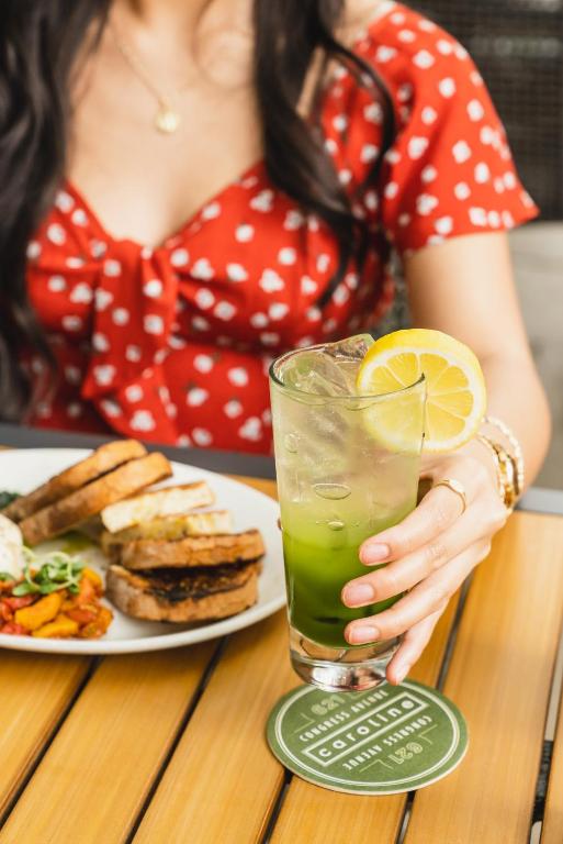 a woman sitting at a table with a drink and a plate of food at Aloft Austin Downtown in Austin