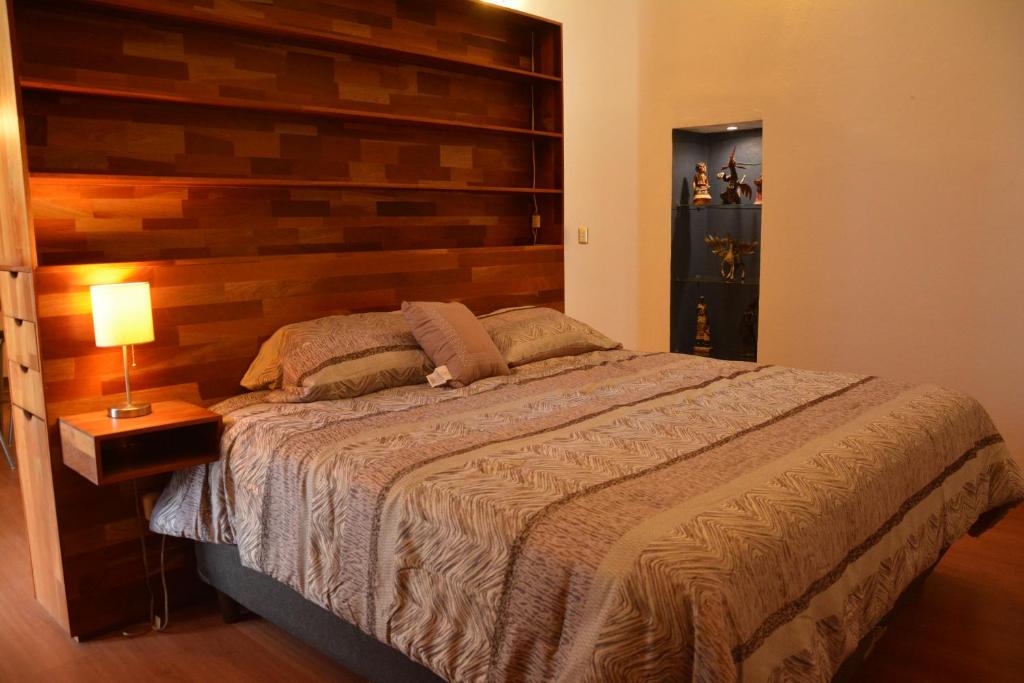 a bedroom with a large bed with a wooden headboard at Hotel Casa San Miguel Arcángel in Oaxaca City