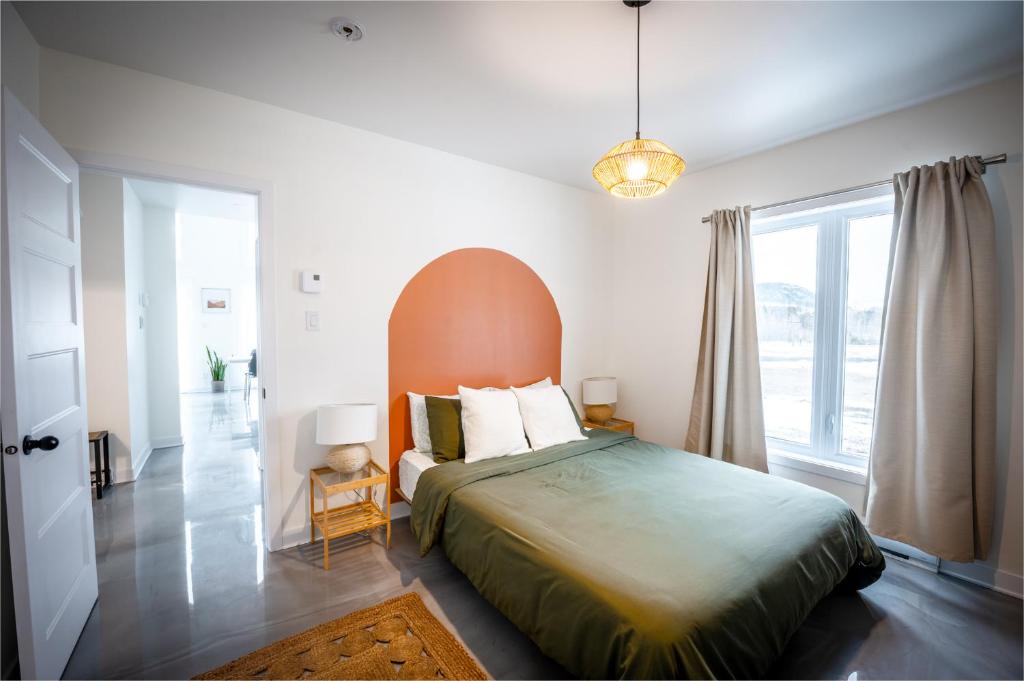 a bedroom with a bed and a large window at La Kobber Hüs - Élégance au coeur de la ville in Murdochville